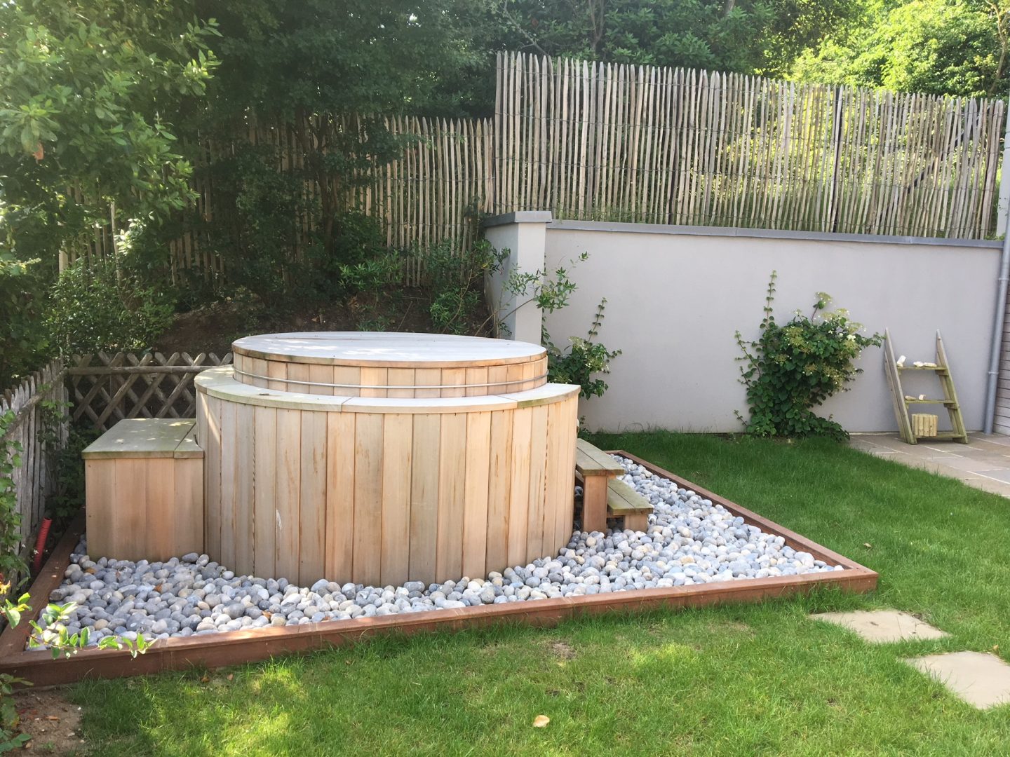 spa aménagé avec coffrage bois et galets dans un jardin